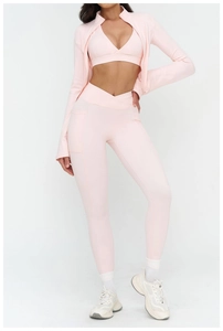 Detailed close-up of light pink yoga set featuring cross waist leggings and zipper jacket