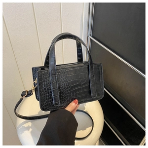 Detail shot of the glossy black crocodile pattern and gold hardware on this square handbag