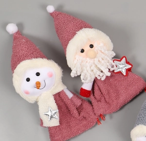 Détail de sacs de Noël en peluche rose avec broderie Père Noël et Bonhomme de neige