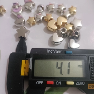Close-up measuring 4.1mm star and heart CCB beads with a digital caliper