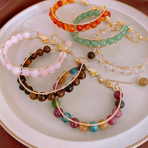 Handmade beaded bracelet with tiger eye stone and butterfly charm on white ceramic plate