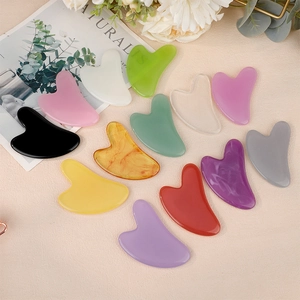 Multiple colors of heart-shaped gua sha tools arranged on a natural aesthetic background