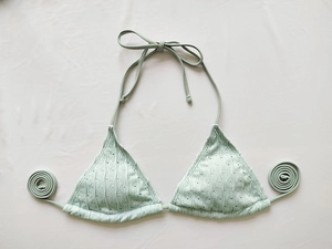 Detail eines hellgrünen gerippten Bikini-Oberteils mit Lochmuster und Neckholder