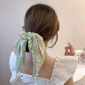 Floral bow hair scrunchie with long ribbons and pearl pendants worn on a ponytail