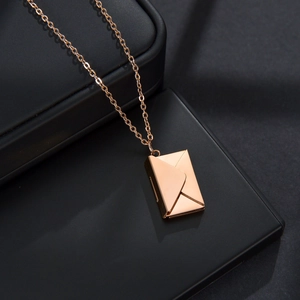 Macro shot of rose gold envelope locket pendant on a premium black matte jewelry box