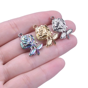 Three stainless steel rose pendants in gold, silver, and rainbow colors held in hand