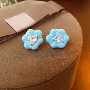 Detail showing blue enamel flower earrings with heart-shaped zircon center and gold trim