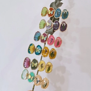 Handmade resin rings with dried flowers and butterflies on a plant stem branch