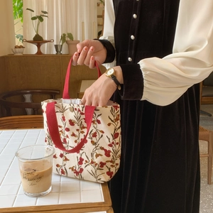 Close-up of red floral corduroy tote bag with magnetic clasp and red fabric handles
