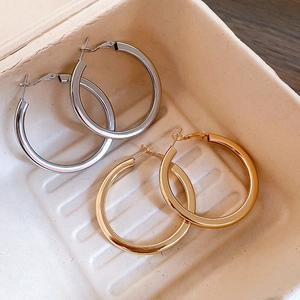 Detail view of large gold and silver polished hoop earrings set in a gift box
