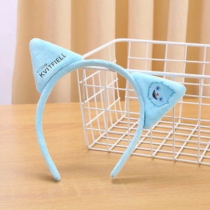 Detail of blue plush cat ear headband with cute monster pattern and Kvitfjell text logo