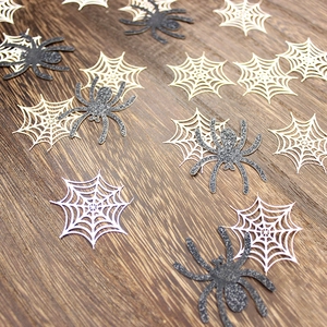 Glittery black spiders and white spider webs on dark wood for Halloween party decor