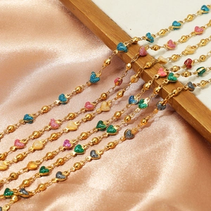 Golden bead chain necklaces with colorful glitter heart pendants on orange silk background