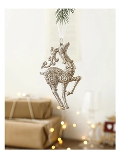 Detail of glittery gold reindeer Christmas ornament hanging from a green pine branch