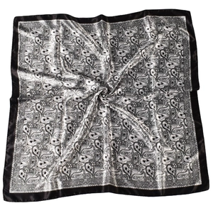 Detailed view of paisley patterns and black satin edges on a silk-like square scarf