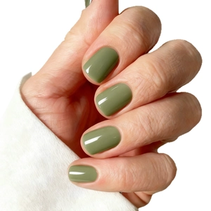 Glossy olive green short square press-on nails shown on hand with white knit sleeve