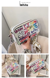Close-up of white crossbody bag featuring colorful graffiti prints and a wide jacquard strap