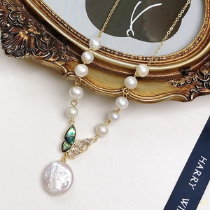 Baroque pearl necklace with crystal butterfly clasp on a luxury velvet backdrop
