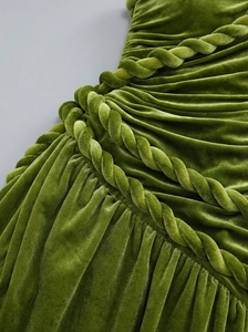 Close-up of moss green velvet fabric featuring intricate pleats and braided rope details