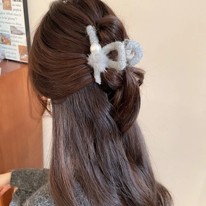 Detail der grauen Plüsch-Haarklammer mit Perle und Fellball in einer eleganten Frisur