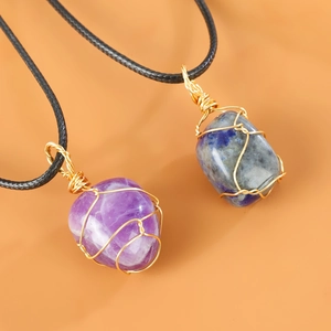 Detail van handgewikkelde amethist en lapis lazuli kristallen hangers in goud