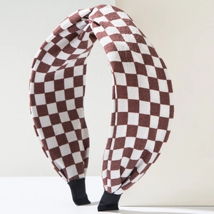 Brown and white checkerboard headband with top knot detail on geometric stone blocks
