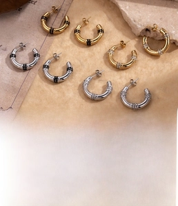Close-up of C-shaped titanium steel hoop earrings featuring inlaid black and white zircons