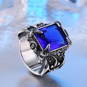 Macro shot of retro men's steel ring with blue gemstone and dragon claw engraving