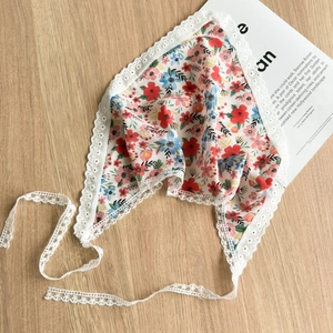 Detailed view of floral headscarf with white lace trim on a wooden background