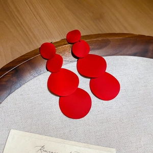 Detail view of red multi-layered round matte earrings on minimalist linen background