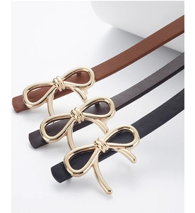 Detail of elegant bow-shaped gold buckles on leather belts in brown, coffee and black