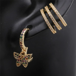Detailed view of gold butterfly earrings and crystal ear cuff on black ear model