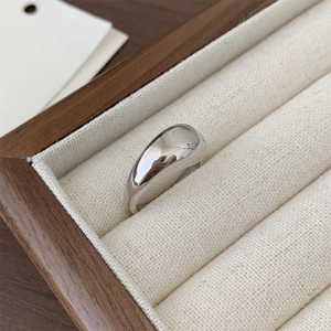 Macro shot of 925 sterling silver wide teardrop ring on a wooden jewelry display case