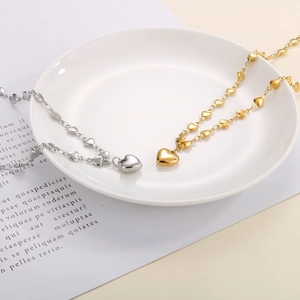 Detailed close-up of heart-shaped link necklaces in gold and silver on white porcelain