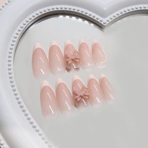 Pink gradient press-on nails with white French tips and 3D bows on a heart mirror