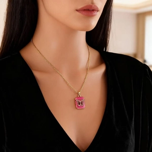Golden stainless steel necklace with pink butterfly pendant worn on woman's collarbone