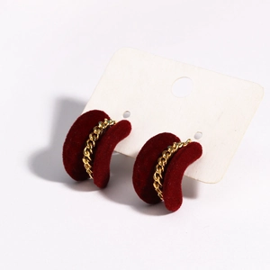 Macro shot of red velvet C-shaped earrings with gold chain detail on white display card