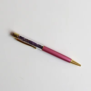 Macro detail of pink crystal ballpoint pen with purple amethyst stones and gold accents
