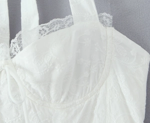 Détail de la broderie en dentelle blanche et des fines bretelles sur une robe de style français