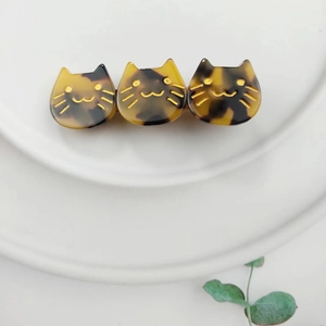 Detail of three-headed cat hair clip featuring amber tortoise pattern and gold accents