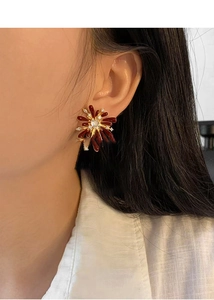 Detailed view of model wearing burgundy enamel and zircon firework stud earrings