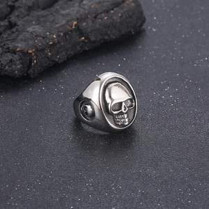Detailed close-up of a punk style stainless steel skull ring on a dark charcoal background