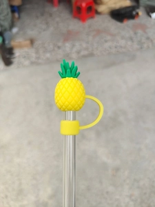 Detail showing a yellow pineapple silicone straw topper with protective dust cap