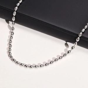 Close-up of a silver titanium steel beaded necklace displayed on a black leather stand