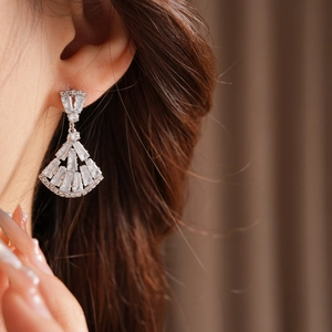 Close-up of fan-shaped silver earring with clear baguette zircon stones on a model