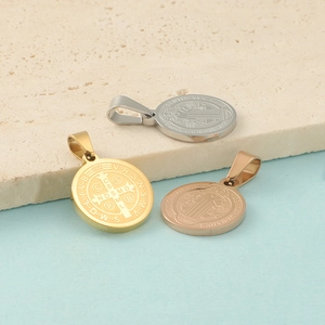 Detailed view of Saint Benedict pendants in silver, gold, and rose gold on a stone plate