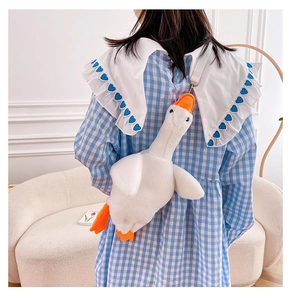 Macro detail of white plush goose bag featuring soft fur and orange beak highlights