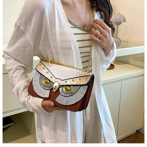 Détail du sac bandoulière hibou avec texture crocodile et accents d'yeux en métal doré