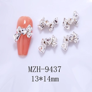 Detailed view of silver bow nail charms with heart zircons, sized 13x14mm on pink nails