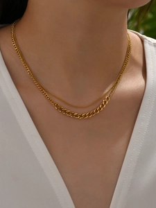 Close-up of double-layer gold necklace with fine chain and heavy Cuban link on model